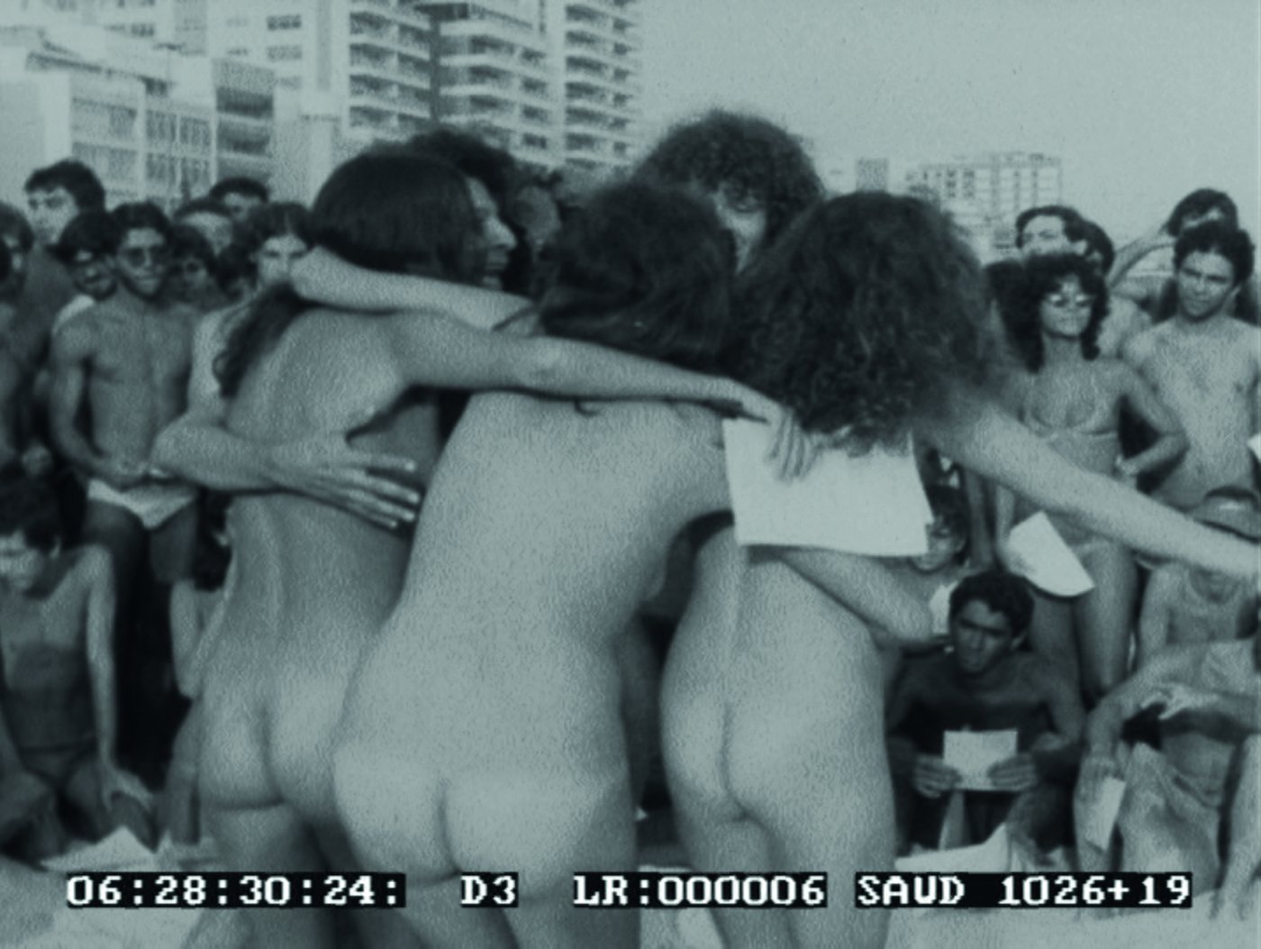 Still photograph from film footage by Sérgio Péo depicting the Porn Art Gang performing Interversão "Pelo Striptease da Arte" [Interversion "For the Striptease of Art"] and the Caminhada Pornô [Porn Walk] on Ipanema Beach, Rio de Janeiro, February 13, 1982. Courtesy of Cairo and Denise Trindade