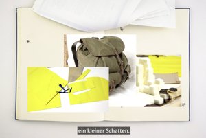 Das Bild zeigt zwei Seiten des Forschungstagebuchs, das den schriftlichen Teil der Dissertation begleitet. Die Künstlerin hat auf diesen Seiten einige Fotos als Collage über den Wiederherstellungsprozess des Rucksacks ihres Großvaters, den er während der Zwangsarbeit trug, platziert.