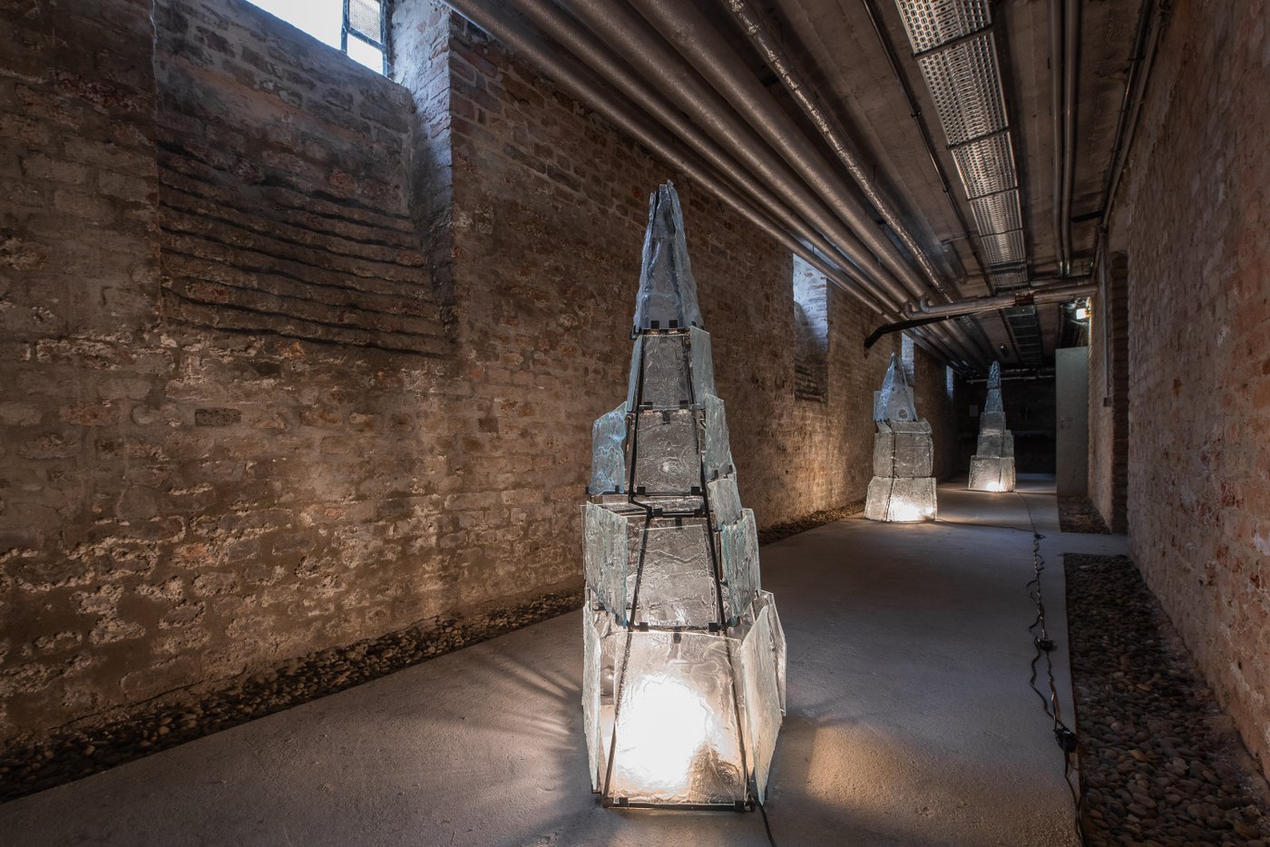 basement corridor with brick walls with three glass pyramids illuminated from the inside with light