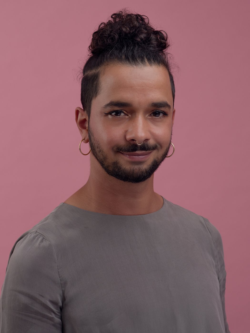 Foto eines jungen Mannes mit dunklen Haaren vor rosa Hintergrund