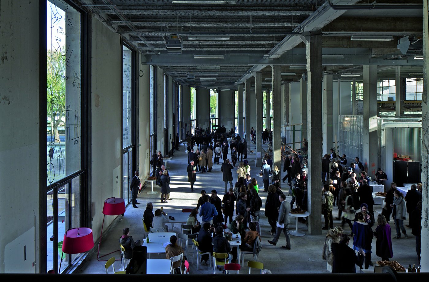 View into a concrete hall with people distributed in the space.