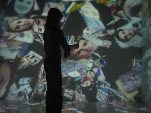 User interacting in 3D through a tweezers interface with virtual images streamed from the internet inside the CAVE environment, ANIMAX Theater, Bonn, 2002