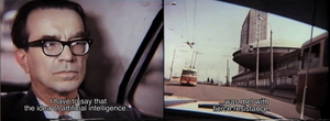 Filmstill of a man with glasses driving a car