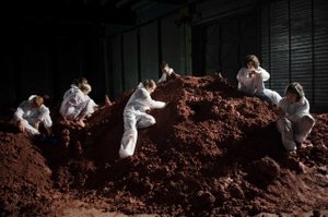 Women in white overalls on a mountain of earth