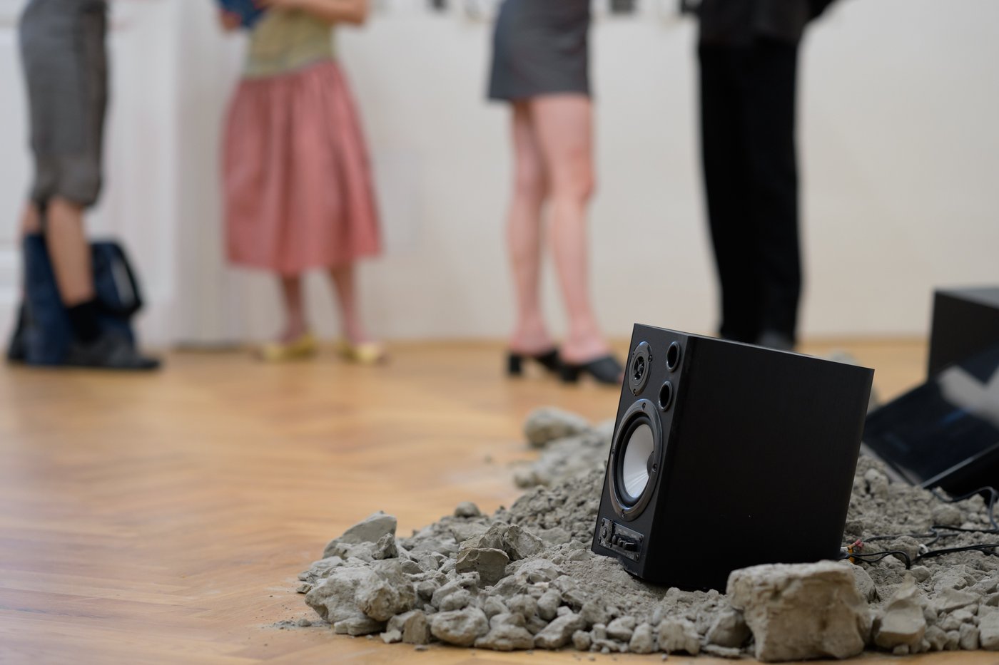 sound boxes on the floor on black sand, in the background people standing