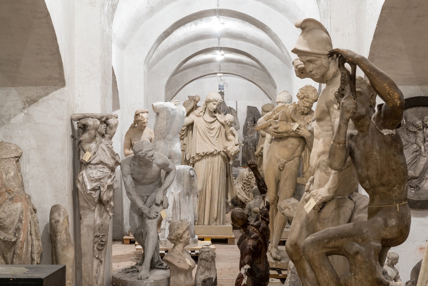 Photo of a room with vaults in which several Greek sculptures in different poses are standing close to each other