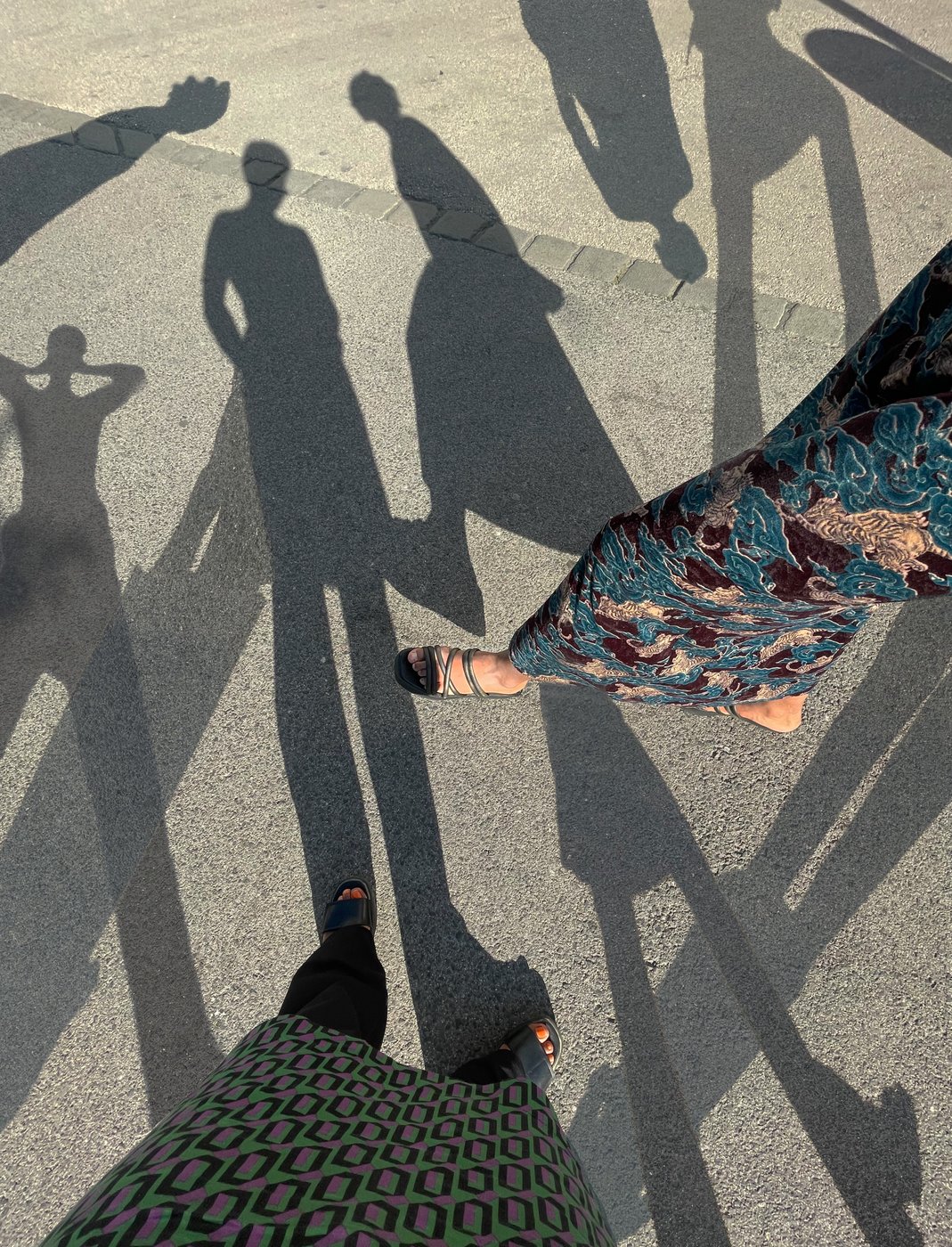 Picture of people on the street, you can see the shadows on the floor and parts of feet