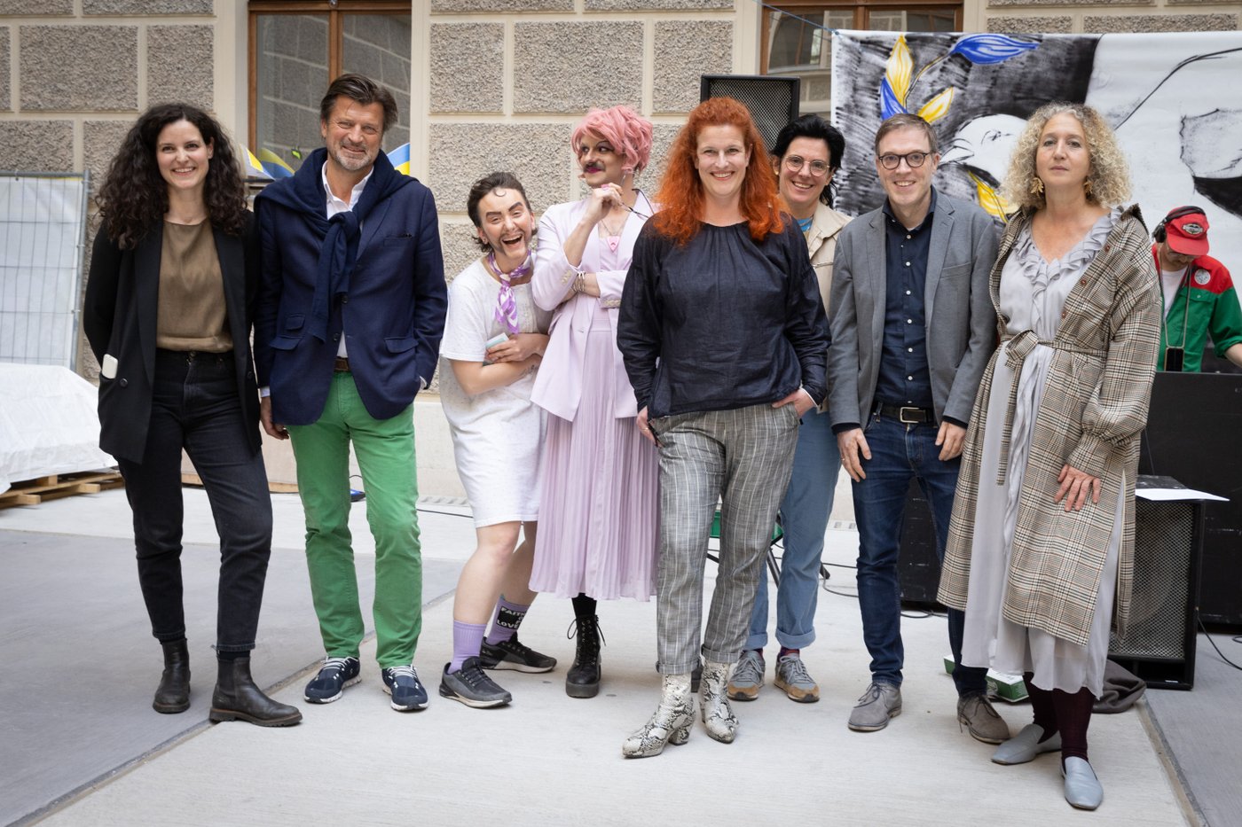 Picture of seven people posing in the courtyard of the Academy building at the Schillerplatz and smiling into the camera