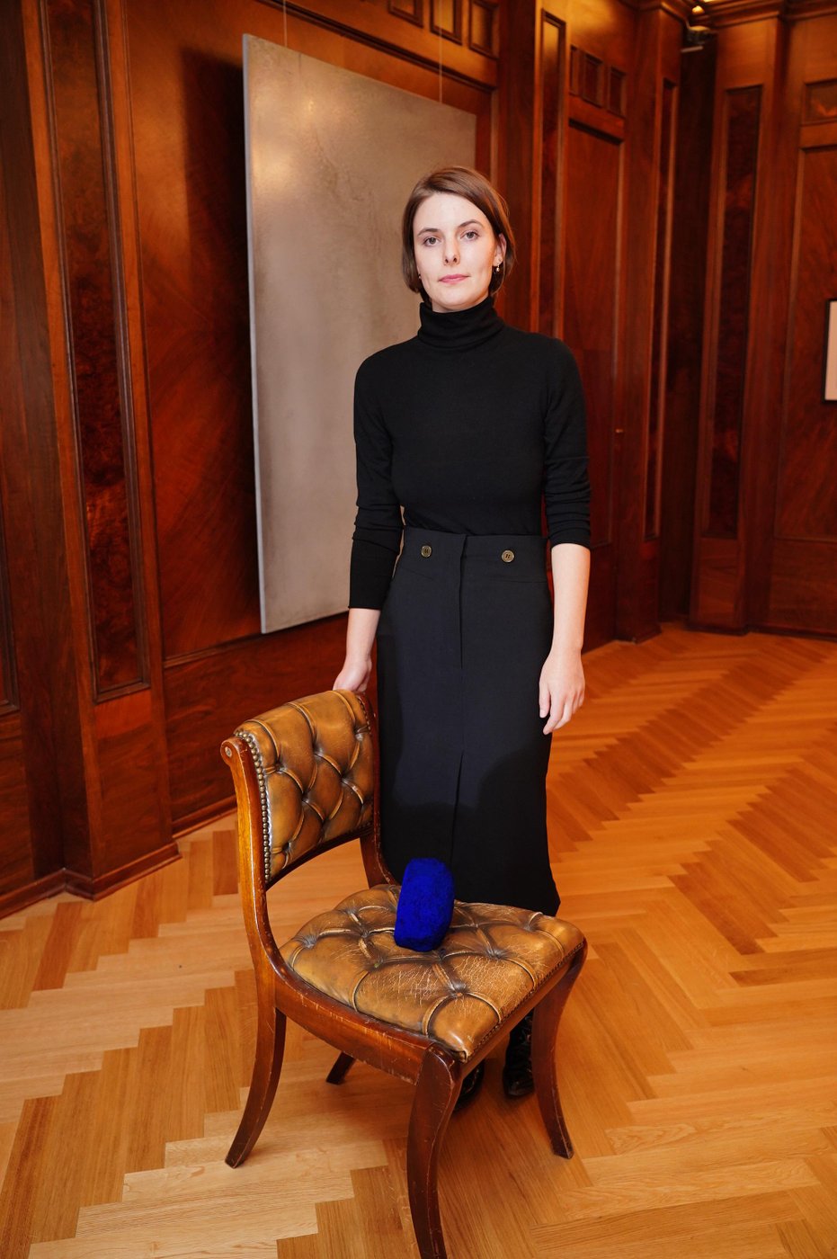 Woman in a black dress with award on a chair