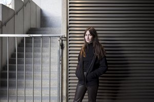 Women with dark clothes and hair standing next to a staircase