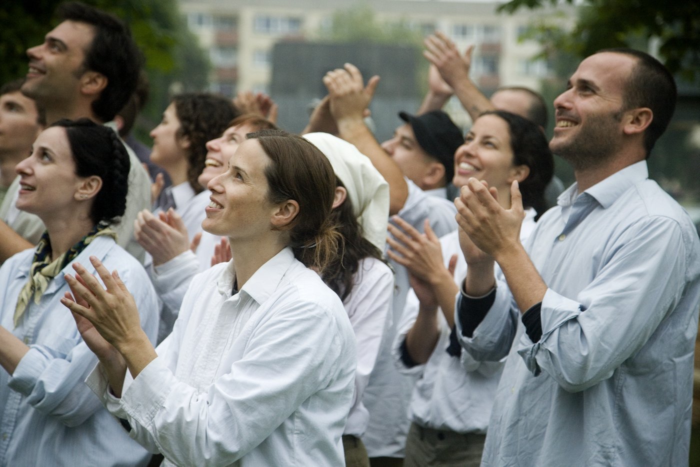 Radiant people in white robes clapping, beaming and looking up.